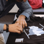 A man places transfer foil with white toner on a black hoodie